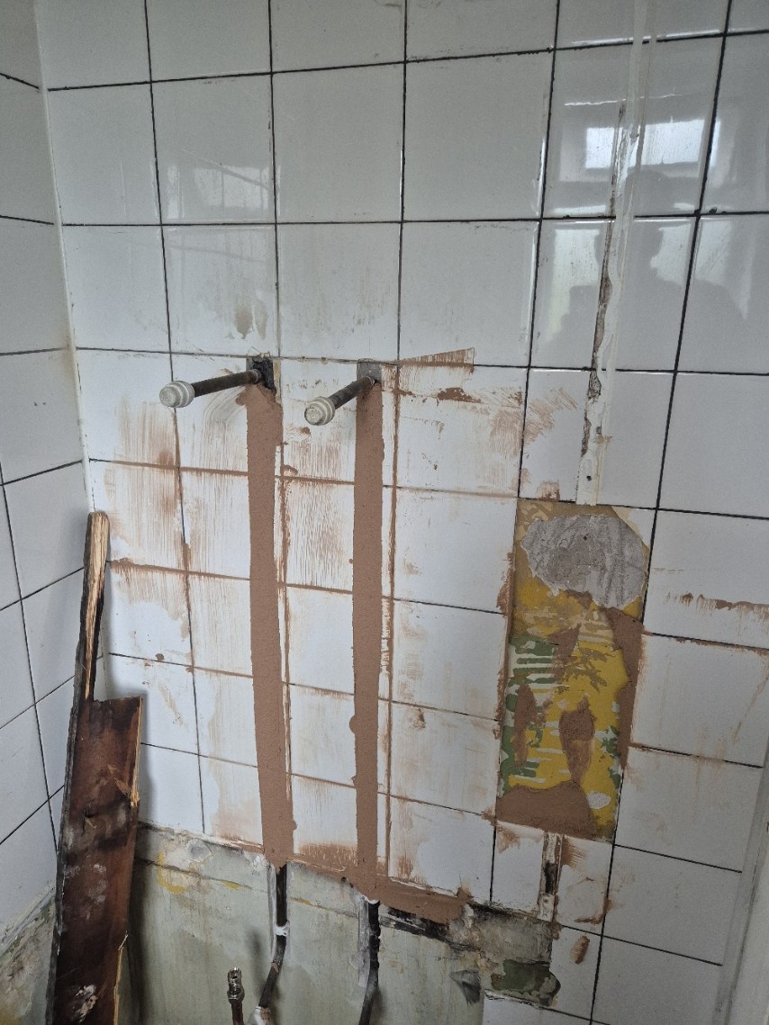 Hot and cold pipework brought through the wall with chased areas made good ready for finishing