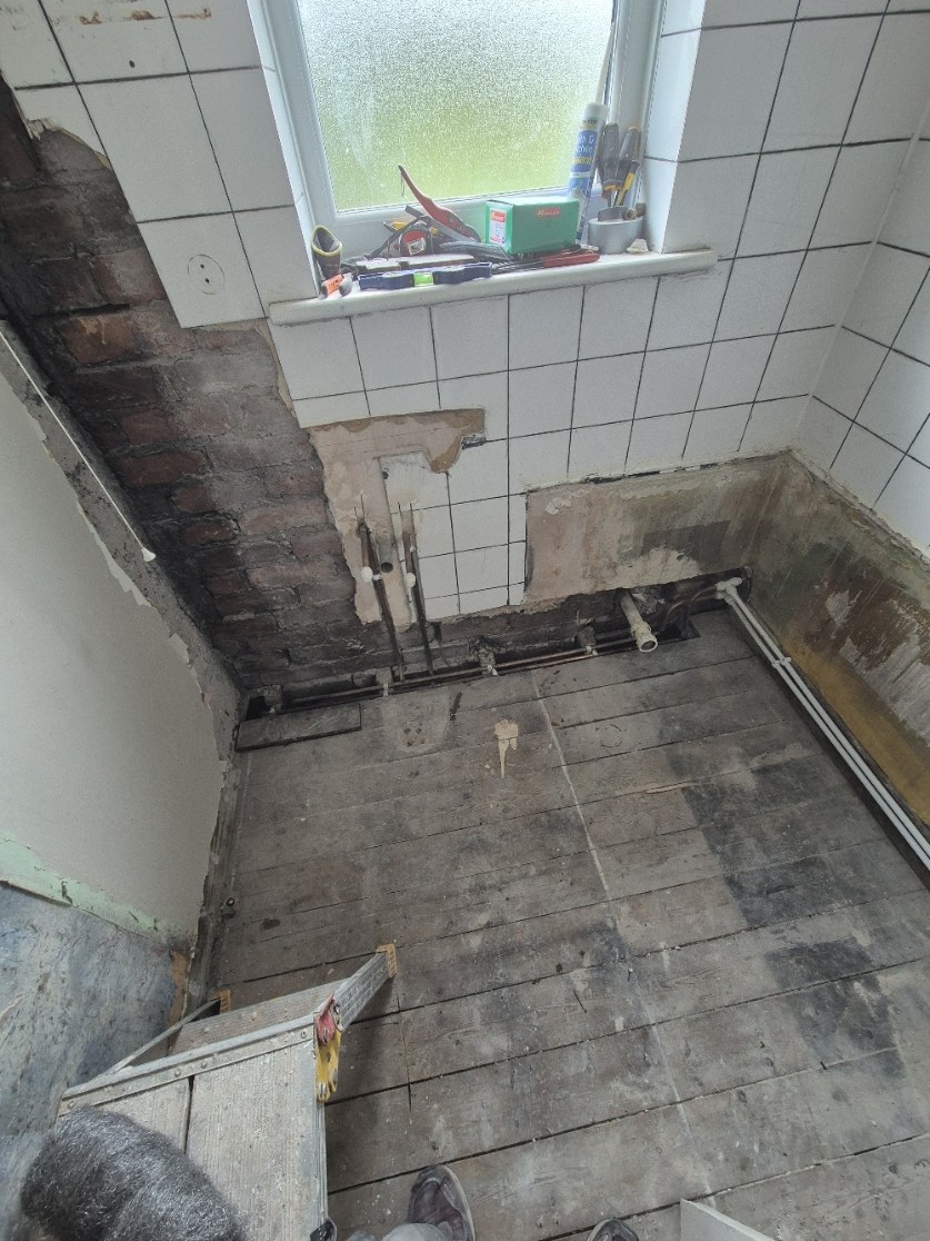 Floor-level pipework and waste routes exposed and prepared for the new bathroom layout